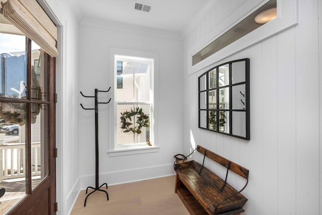 doorway to outside featuring crown molding, wood finished floors, visible vents, and baseboards