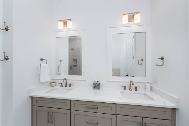 full bathroom featuring double vanity, a shower with shower door, and a sink