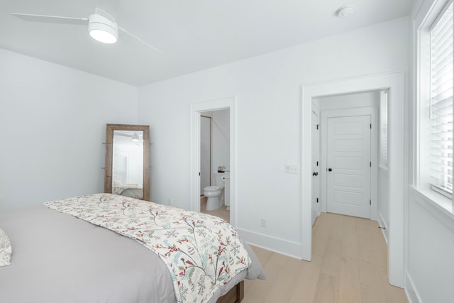 bedroom featuring light wood-style flooring, multiple windows, baseboards, and connected bathroom