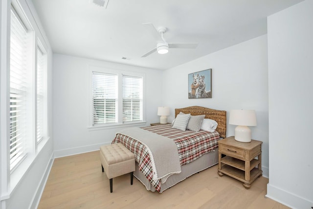 bedroom with a ceiling fan, visible vents, wood finished floors, and baseboards