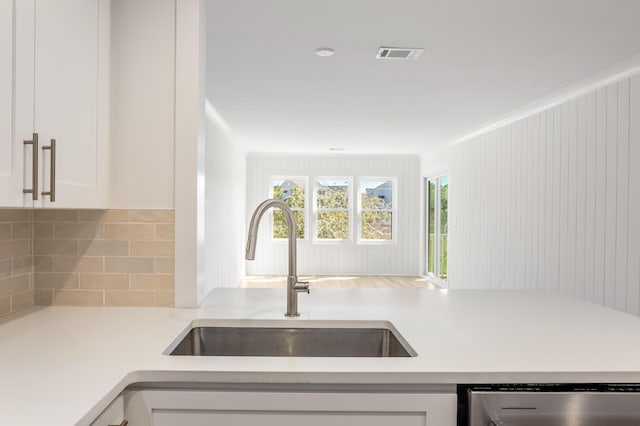 kitchen featuring visible vents, dishwasher, light countertops, white cabinetry, and a sink