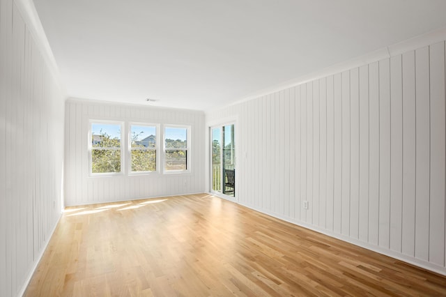 empty room with light wood finished floors and crown molding