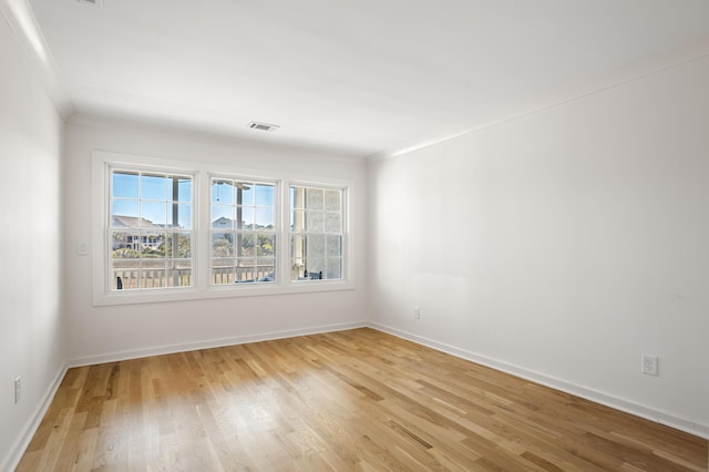 unfurnished room featuring ornamental molding, light wood-type flooring, visible vents, and baseboards