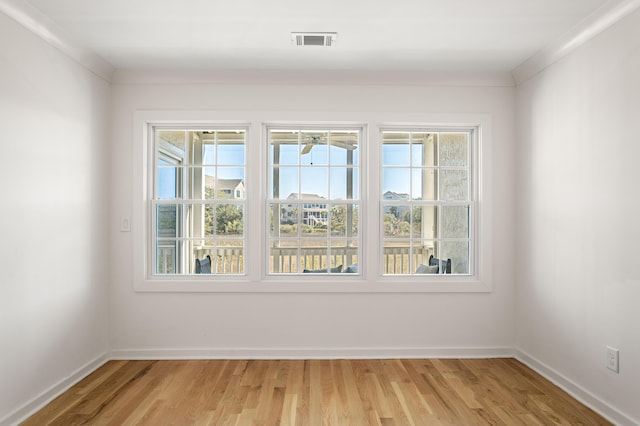 unfurnished room with light wood-type flooring, visible vents, and baseboards