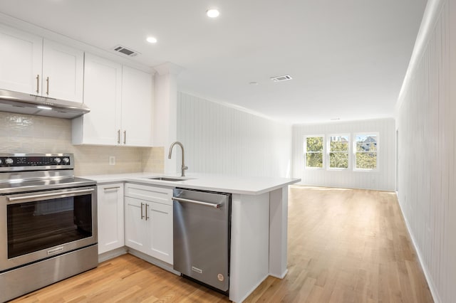 kitchen featuring under cabinet range hood, stainless steel appliances, a peninsula, visible vents, and white cabinetry