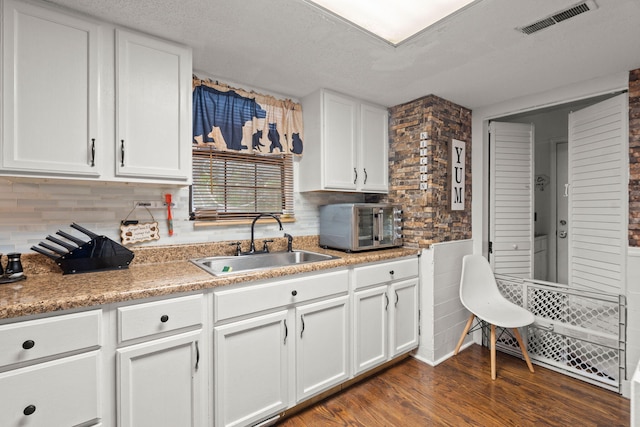 kitchen featuring sink, white cabinetry, dark hardwood / wood-style floors, and decorative backsplash