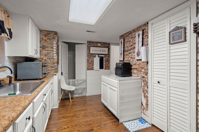 kitchen with white cabinets, dark hardwood / wood-style flooring, sink, and a textured ceiling