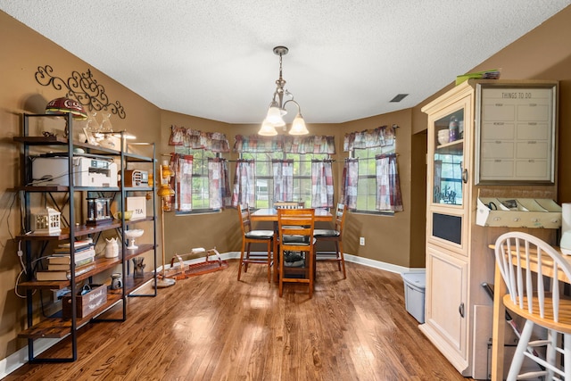 dining space featuring a notable chandelier, a textured ceiling, plenty of natural light, and hardwood / wood-style floors