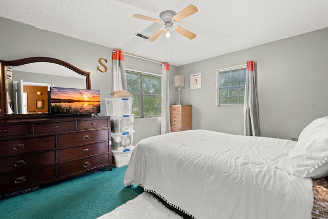 carpeted bedroom with ceiling fan and a textured ceiling