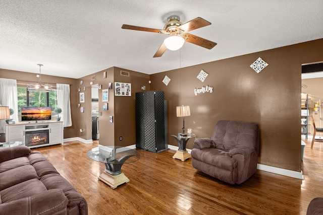 living room with ceiling fan, hardwood / wood-style flooring, and a textured ceiling