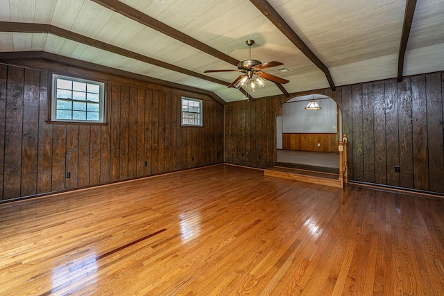 additional living space featuring plenty of natural light, wood walls, a ceiling fan, and hardwood / wood-style flooring