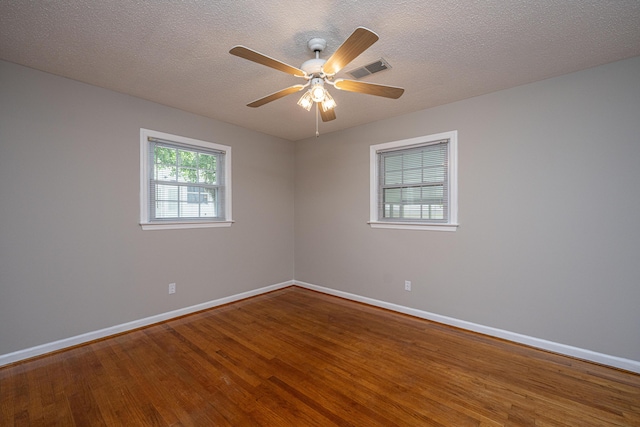 unfurnished room with a ceiling fan, visible vents, wood finished floors, and baseboards