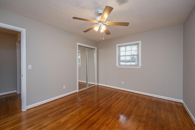 unfurnished bedroom featuring wood finished floors, a ceiling fan, a closet, visible vents, and baseboards