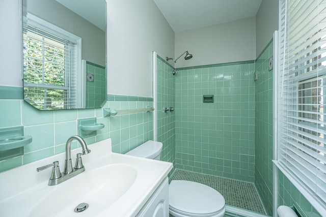 bathroom with toilet, tile walls, a sink, and a shower stall