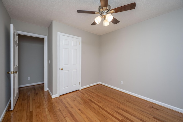 unfurnished bedroom with baseboards, light wood-style flooring, ceiling fan, and a textured ceiling