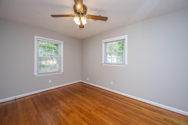 spare room with wood finished floors, baseboards, a ceiling fan, and a healthy amount of sunlight