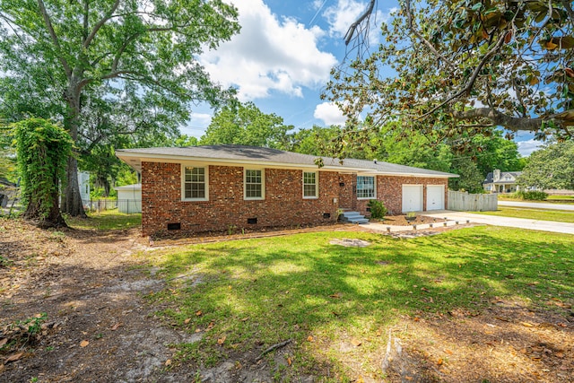 back of property featuring a yard, driveway, brick siding, a garage, and crawl space