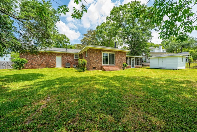 back of property featuring brick siding, a sunroom, fence, and a lawn