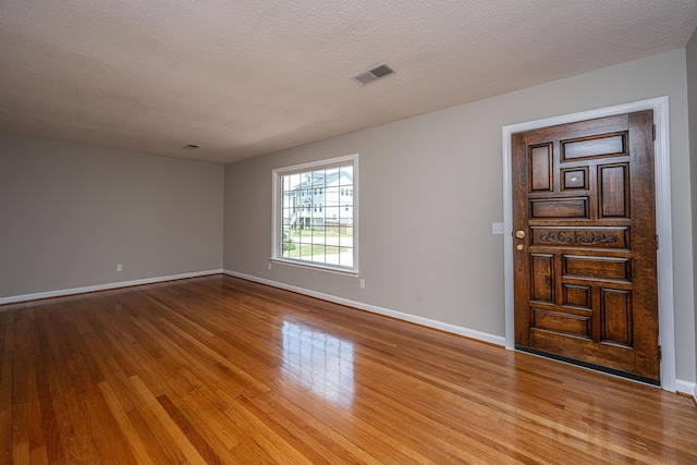 spare room with baseboards, visible vents, and wood finished floors