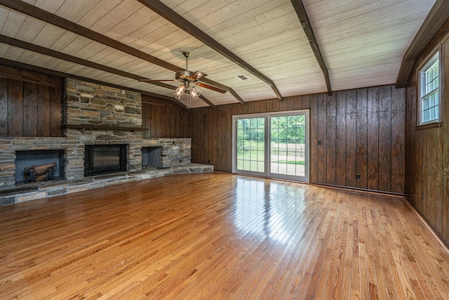 unfurnished living room with wood finished floors, plenty of natural light, a fireplace, and beamed ceiling