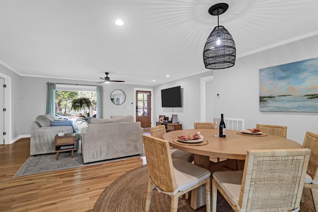 dining space featuring crown molding, wood-type flooring, and ceiling fan