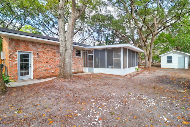 back of house with a sunroom and a storage unit