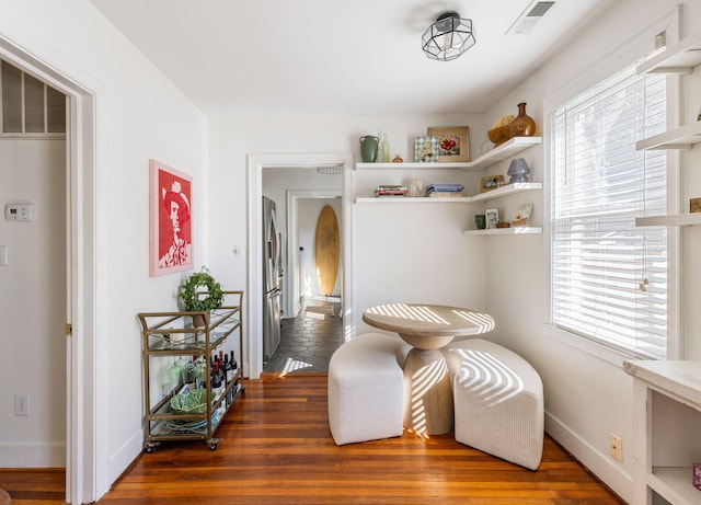 living area featuring visible vents, baseboards, and wood finished floors