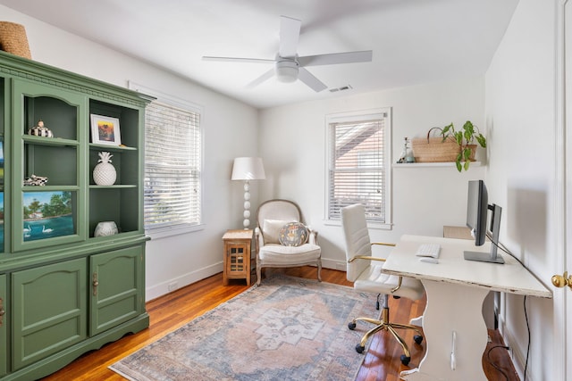 office area featuring ceiling fan, plenty of natural light, wood finished floors, and visible vents