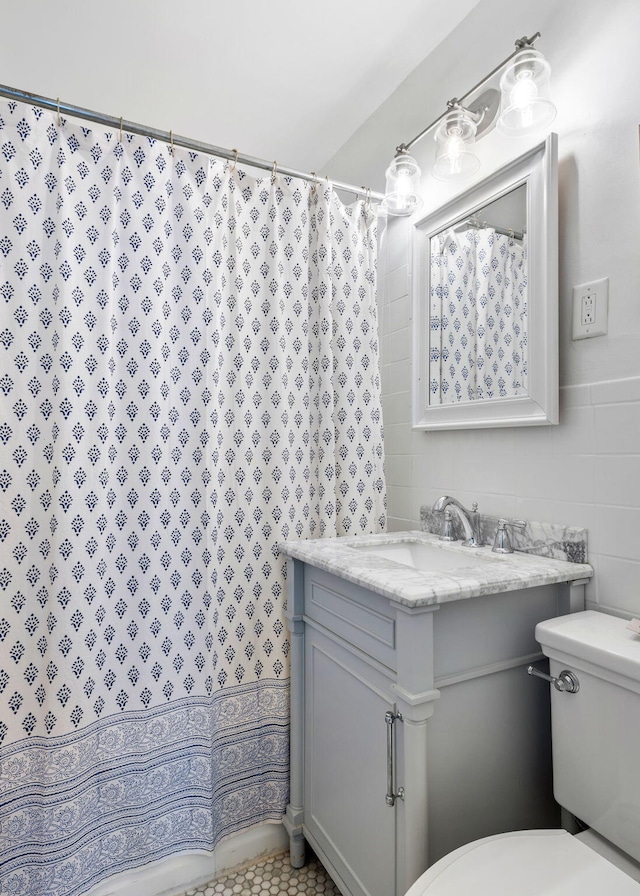 bathroom with toilet, curtained shower, vanity, and tile walls