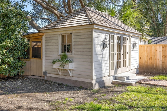 view of outdoor structure with an outbuilding, fence, and entry steps