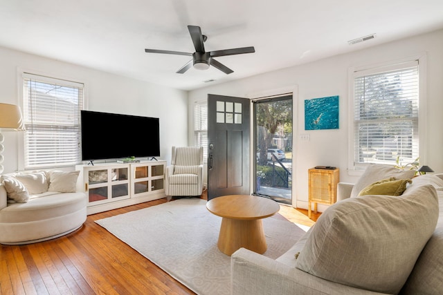 living room with visible vents, ceiling fan, and hardwood / wood-style floors