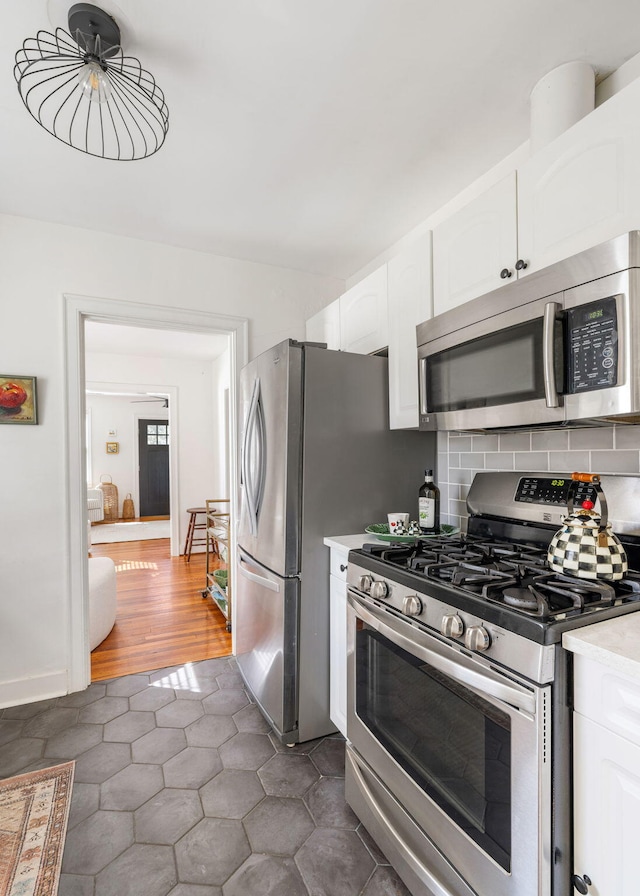 kitchen with light countertops, appliances with stainless steel finishes, backsplash, and white cabinets