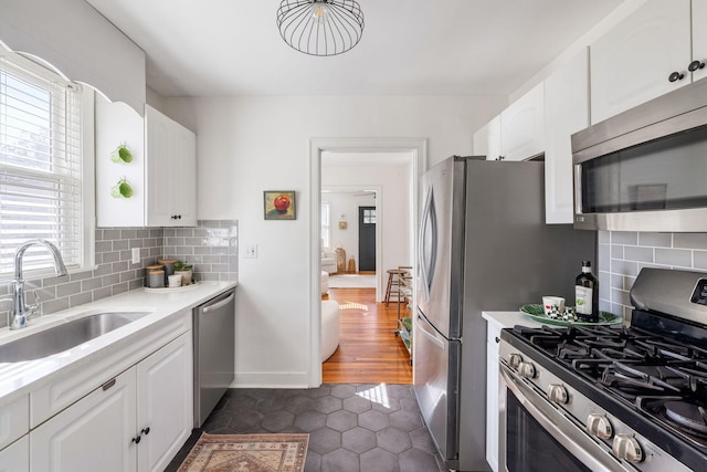 kitchen featuring stainless steel appliances, white cabinets, a sink, and decorative backsplash