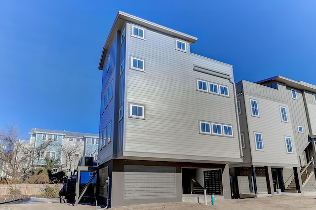 rear view of house with cooling unit, stairs, and fence