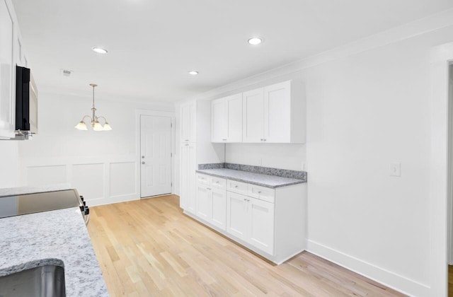 8612 Delhi Rd, North Charleston, SC 29406 - kitchen with white cabinets, light wood-type flooring, a chandelier, recessed lighting, and a wainscoted wall