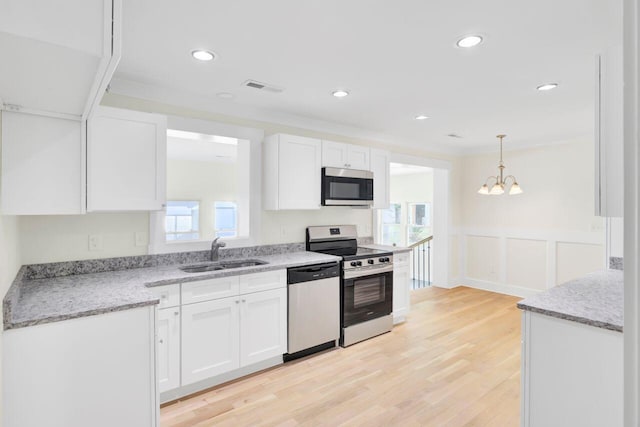 8612 Delhi Rd, North Charleston, SC 29406 - kitchen with stainless steel appliances, a sink, white cabinets, a wainscoted wall, and light wood-style floors