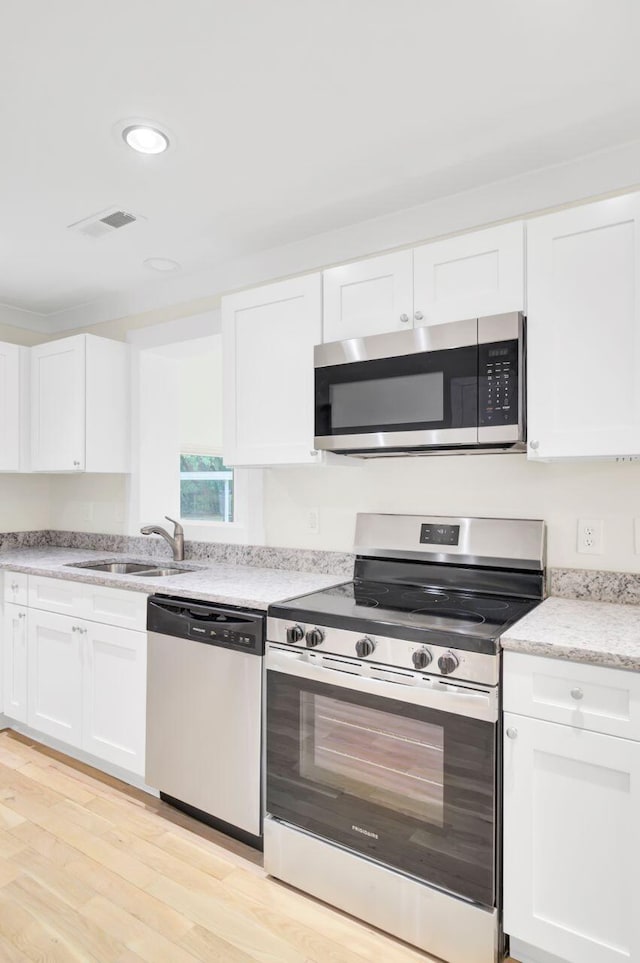 8612 Delhi Rd, North Charleston, SC 29406 - kitchen with stainless steel appliances, a sink, white cabinets, light wood finished floors, and recessed lighting
