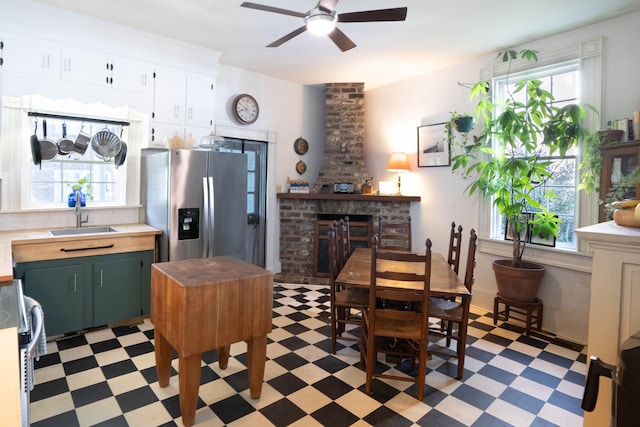 kitchen with green cabinets, sink, stainless steel refrigerator with ice dispenser, a brick fireplace, and range