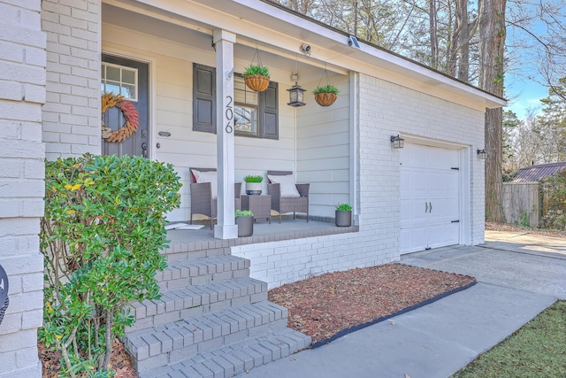 property entrance with a porch, a garage, brick siding, and driveway