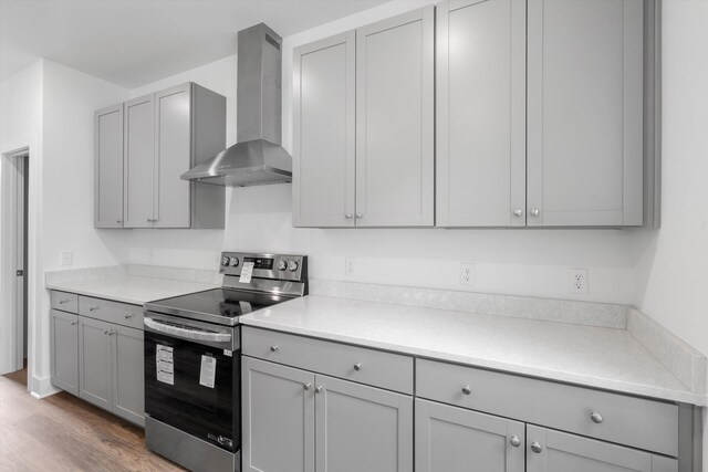1076 Williams Rd, Charleston, SC 29412 - kitchen with stainless steel electric range, wall chimney exhaust hood, gray cabinetry, light wood-style floors, and light countertops