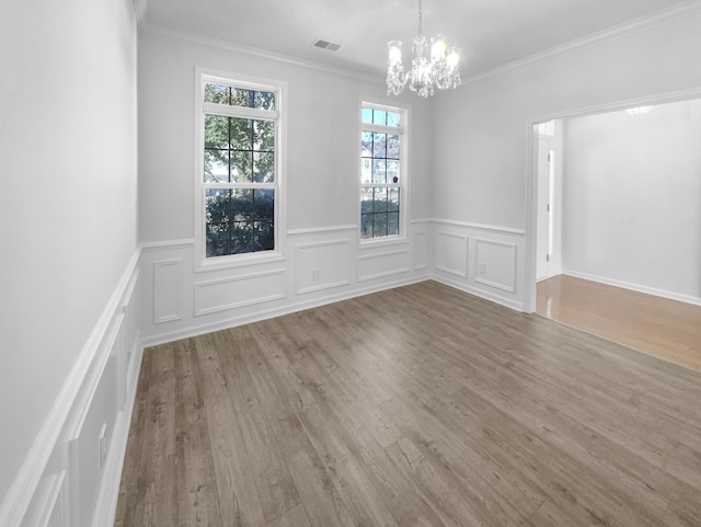 unfurnished room with crown molding, wood finished floors, visible vents, and a notable chandelier