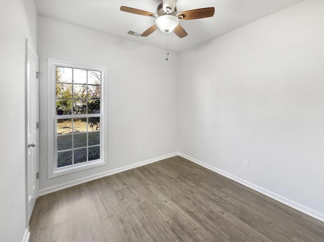 spare room with a ceiling fan, baseboards, visible vents, and dark wood-type flooring