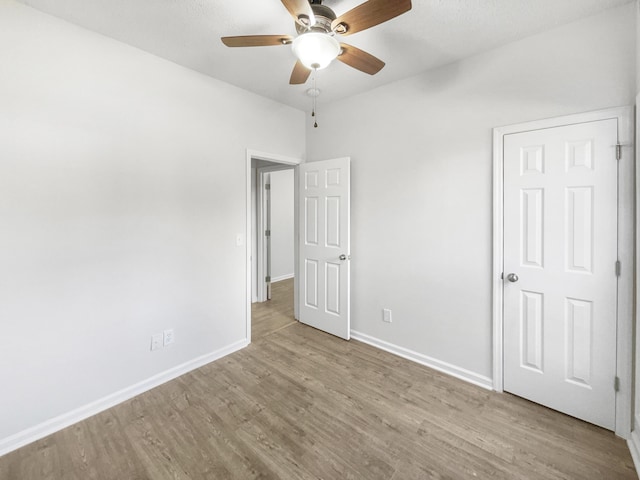 unfurnished bedroom featuring a ceiling fan, light wood-style flooring, and baseboards