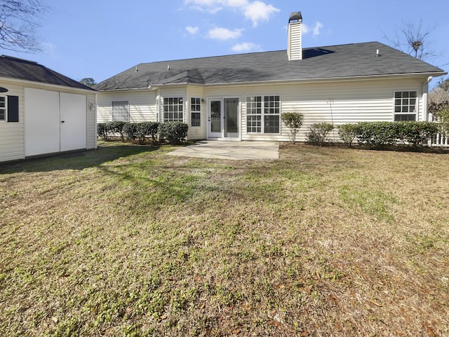 back of house with a patio area, a lawn, and a chimney