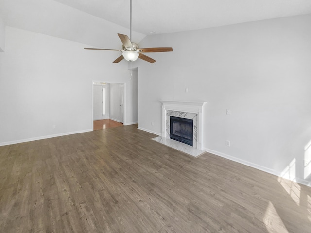 unfurnished living room with a ceiling fan, a high end fireplace, baseboards, and wood finished floors