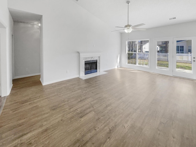 unfurnished living room with visible vents, ceiling fan, a premium fireplace, wood finished floors, and vaulted ceiling