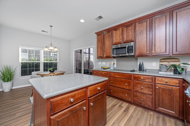 kitchen with sink, appliances with stainless steel finishes, decorative light fixtures, a kitchen island, and washer / clothes dryer