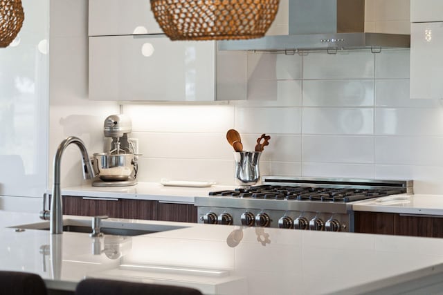 kitchen with backsplash, light countertops, a sink, and stainless steel gas cooktop