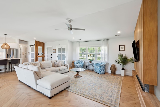 living room featuring a barn door, ceiling fan, recessed lighting, and baseboards