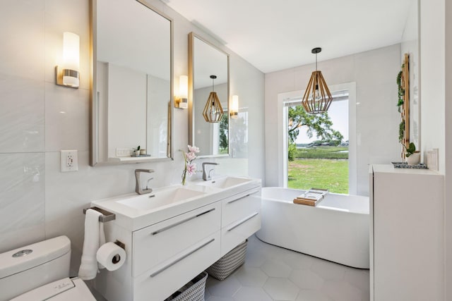 full bath featuring a freestanding tub, toilet, tile patterned flooring, double vanity, and tile walls